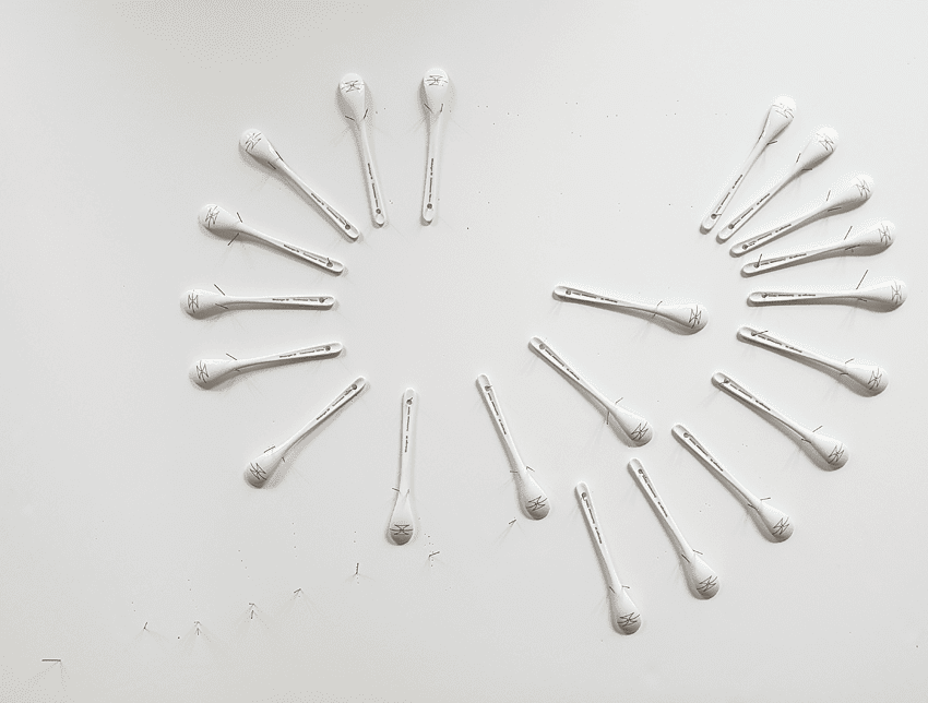 21 Spoons made of porcelain fixed on a grayish-white background, arranged in two half circles