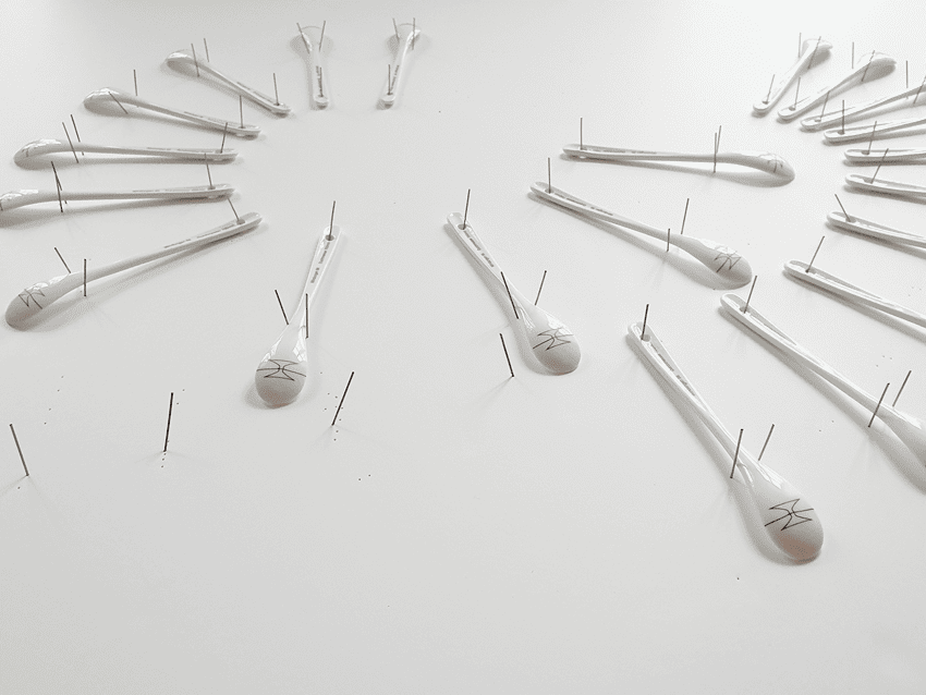 21 Spoons made of porcelain fixed on a grayish-white background, arranged in two half circles